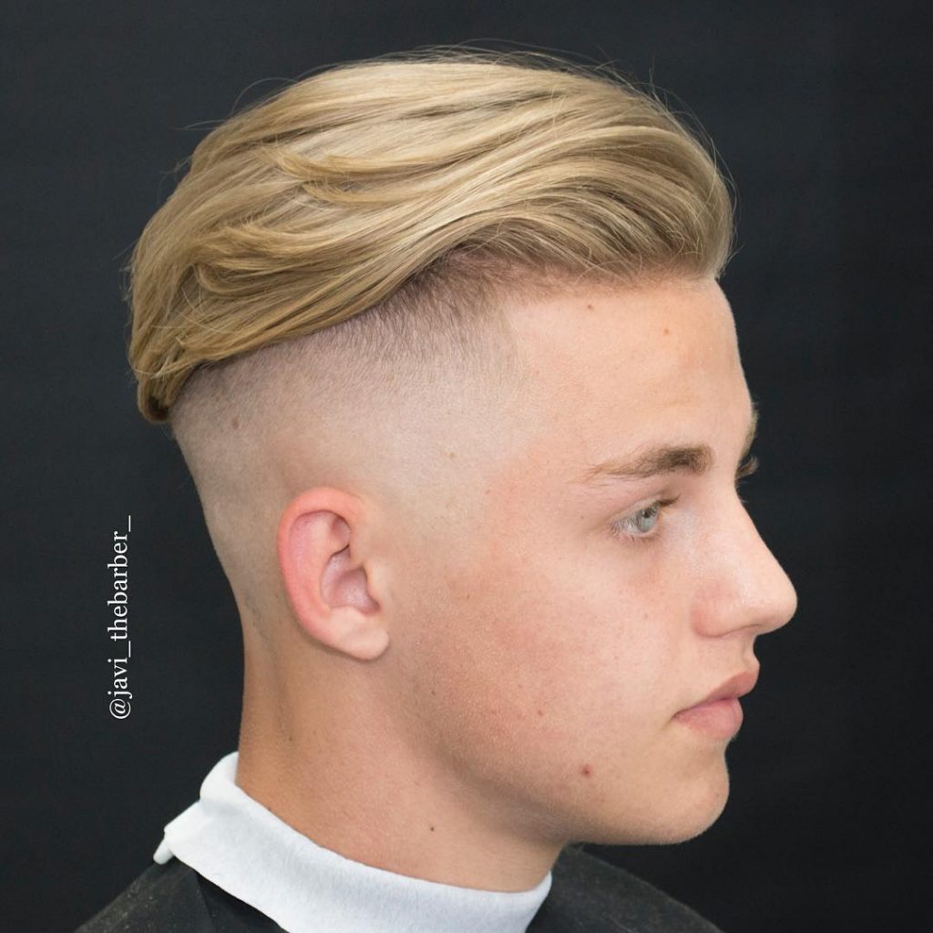 Longer wavy hair styled back undercut for men with high bald fade