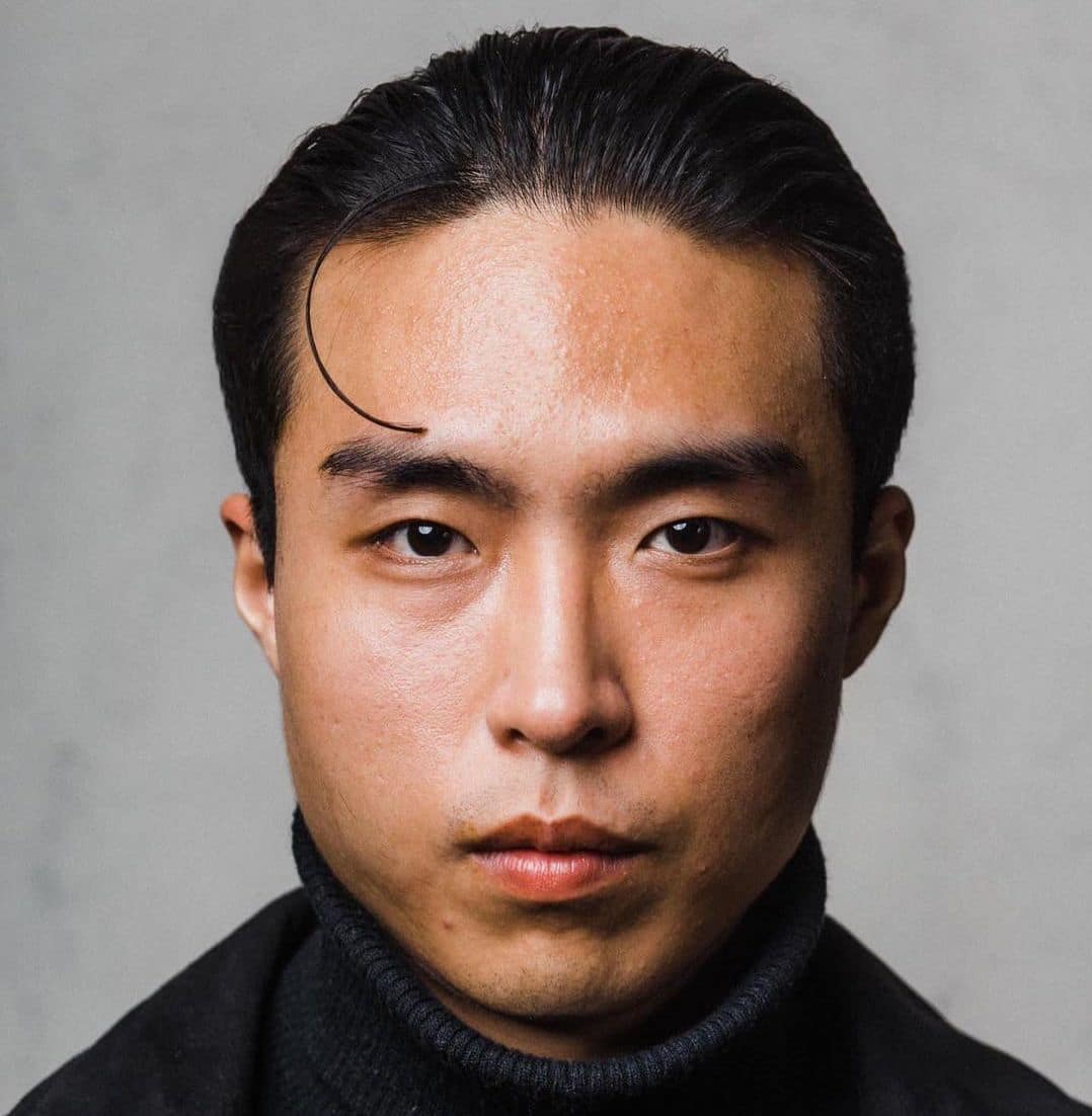 Cool slicked back hair with a 90s style loose tendril for Asian men